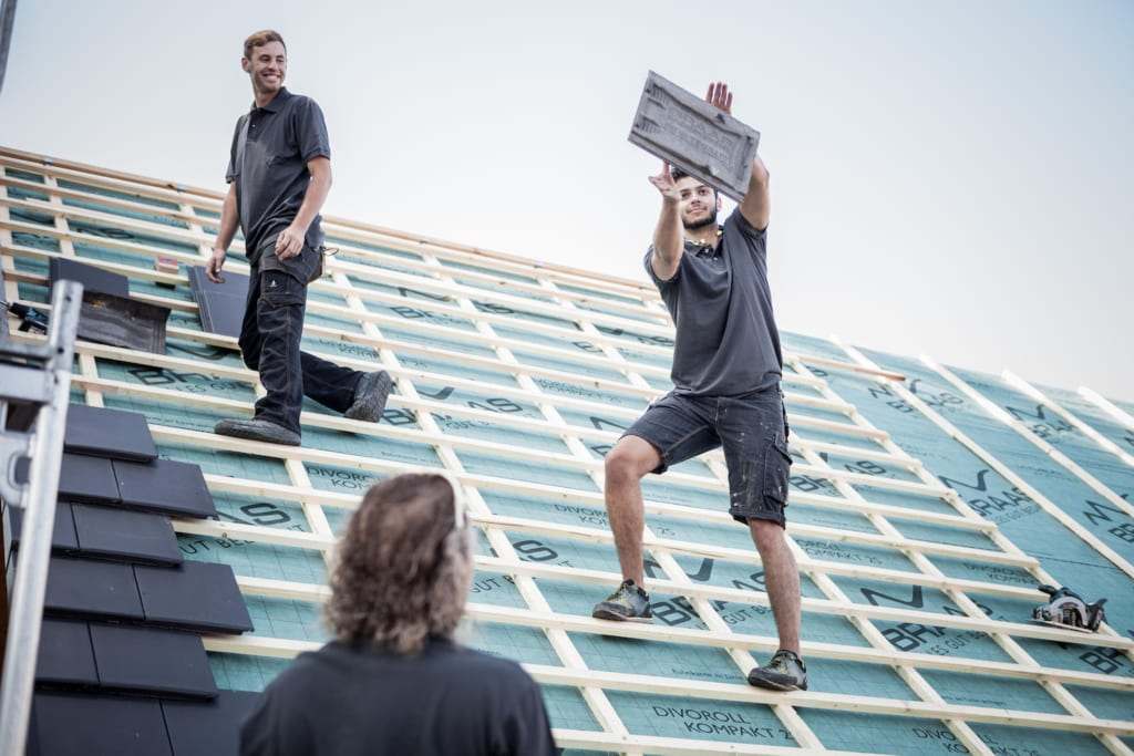Dachdecker tragen und verlegen Ziegel auf der Lattung eines Daches im Bau