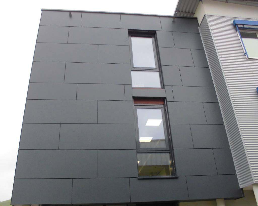 Fassade mit anthrazitfarbenen Plattenelementen und Fenstern