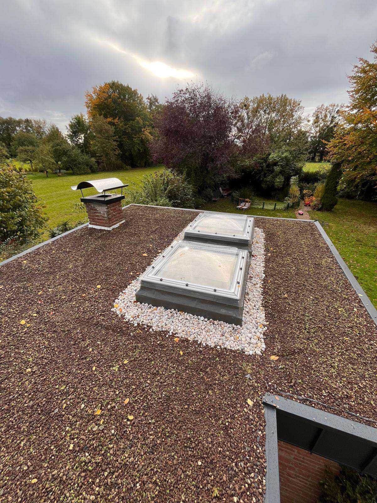 Flachdach mit Kiesauflage, zwei Lichtkuppeln und einem Schornstein von oben