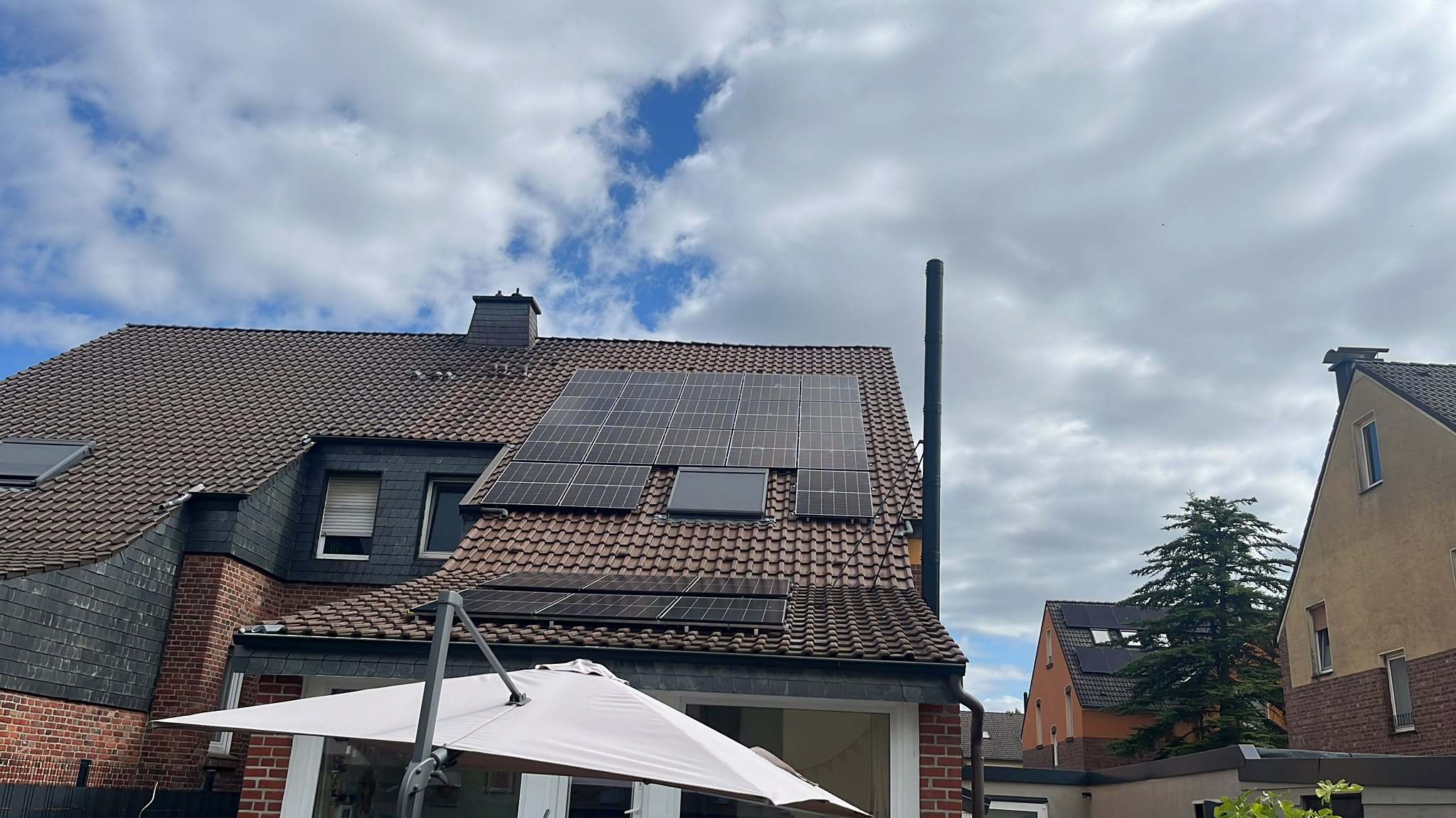 Ziegeldach mit Solarmodulen neben einer schieferverkleideten Gaube