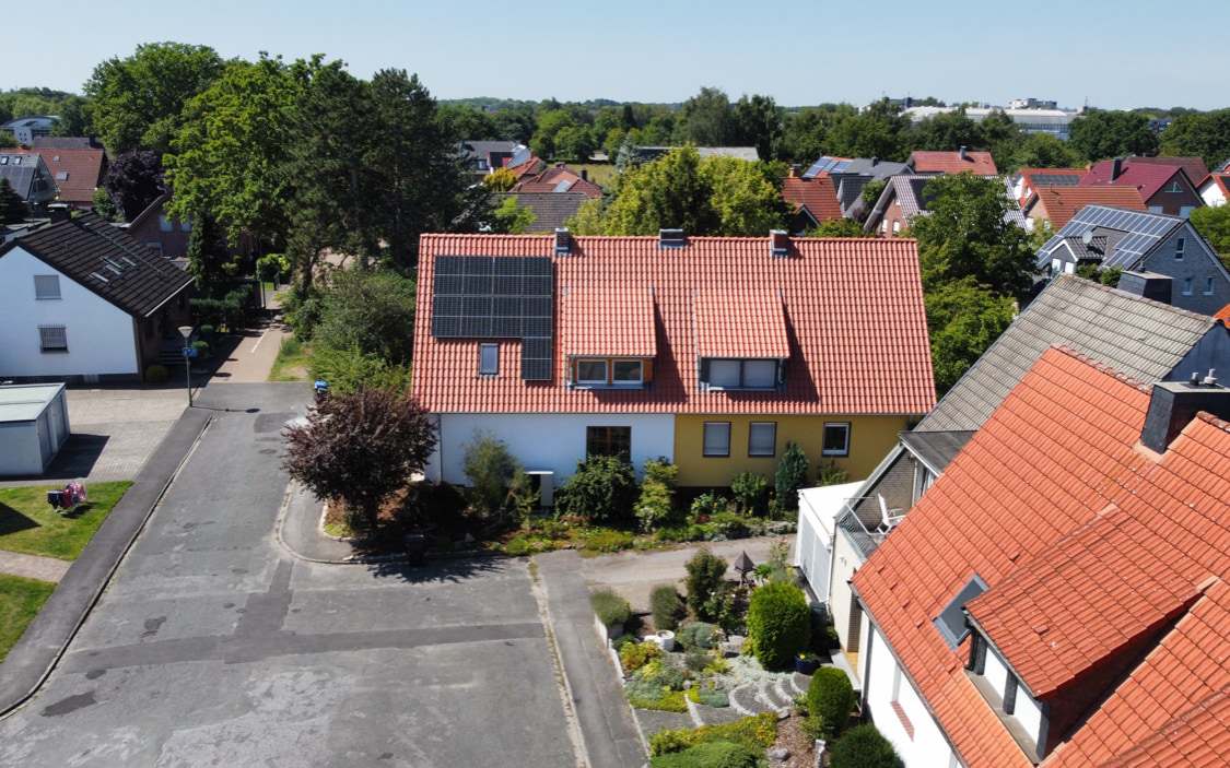 Rotes Ziegeldach eines Wohnhauses mit Solarmodulen, aus der Luft fotografiert